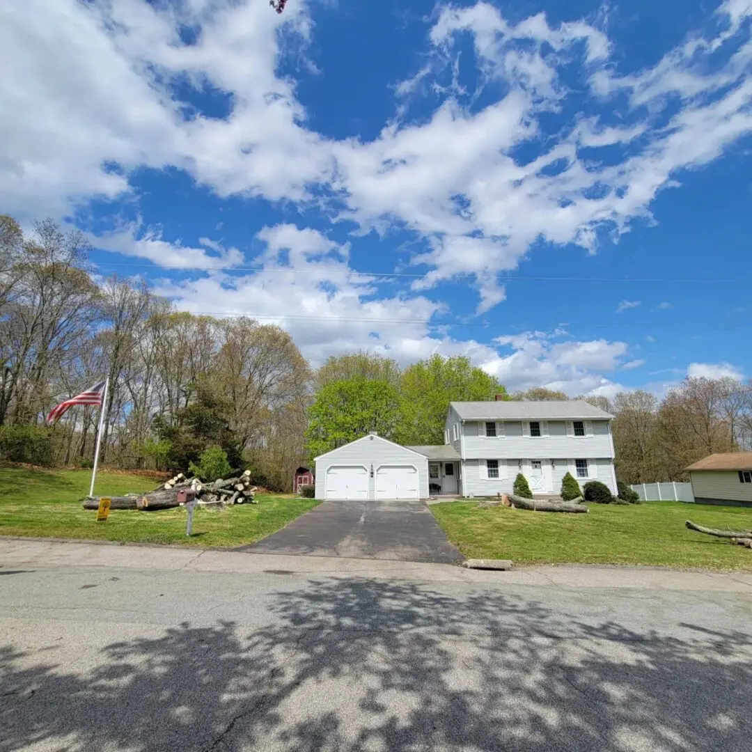 A house with two garage doors and trees in the background.